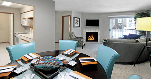 a living room with a table with chairs and a fireplace
